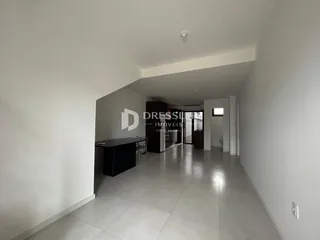 Vista do corredor interno de uma residência com paredes brancas.