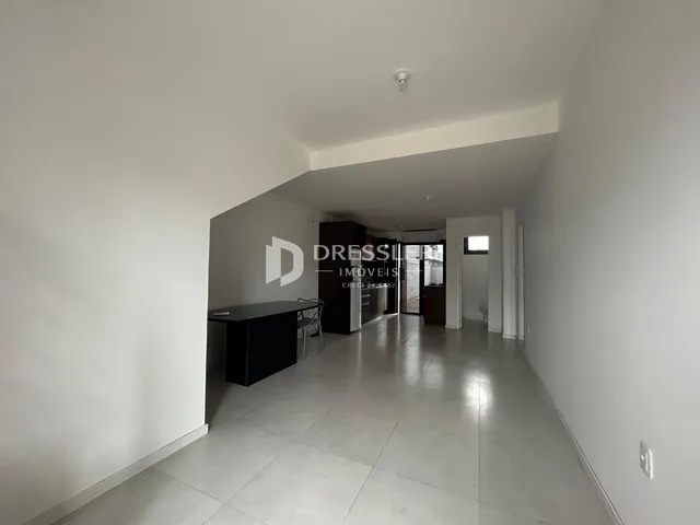 Vista do corredor interno de uma residência com paredes brancas.
