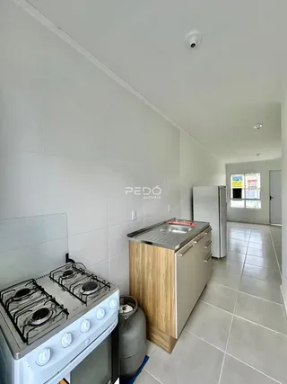 A cozinha apresenta paredes brancas e piso claro.