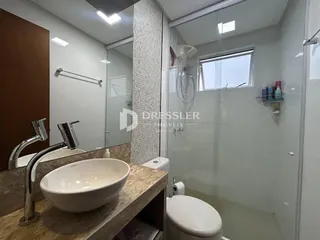Banheiro moderno com box de vidro e pia de mármore.