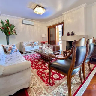 Sala de estar com sofá, poltronas e tapete vermelho decorando o ambiente.