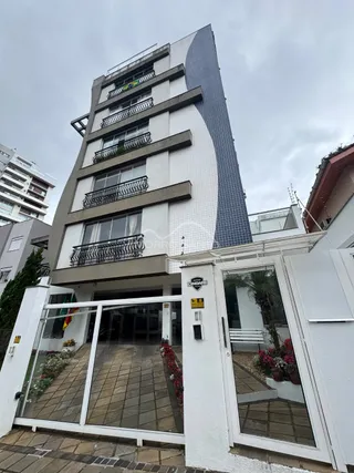 Fachada moderna de um prédio residencial em Lajeado, Brasil, com revestimento branco e detalhes em cinza escuro.