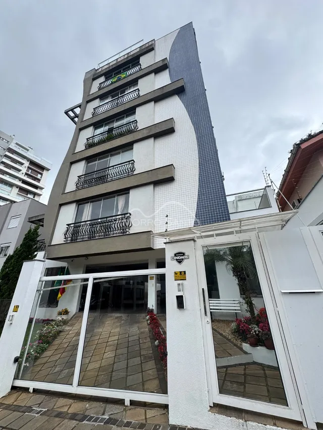 Fachada moderna de um prédio residencial em Lajeado, Brasil, com revestimento branco e detalhes em cinza escuro.