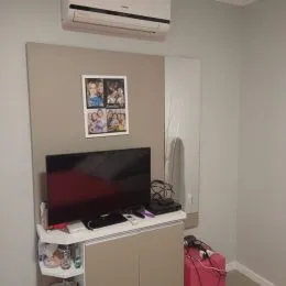 Foto interna mostrando uma parede com televisão e aparelho de ar condicionado.