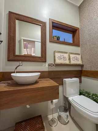Banheiro com bancada de madeira e vaso sanitário branco.