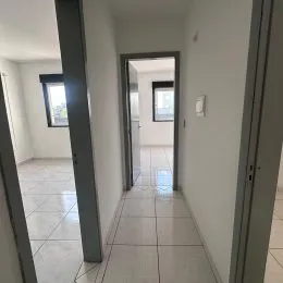 Foto de um corredor interno com piso claro e paredes brancas.