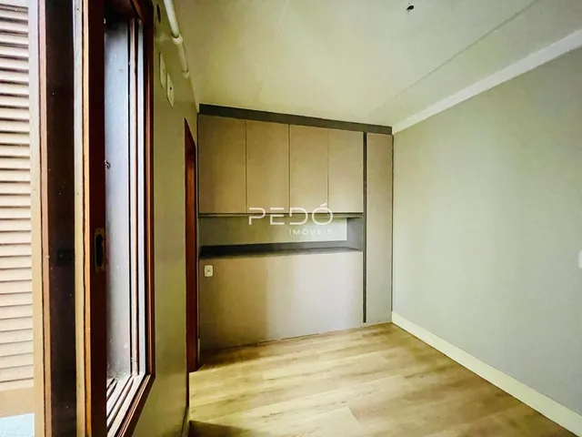A foto mostra o interior de um ambiente com piso de madeira clara e armários embutidos.