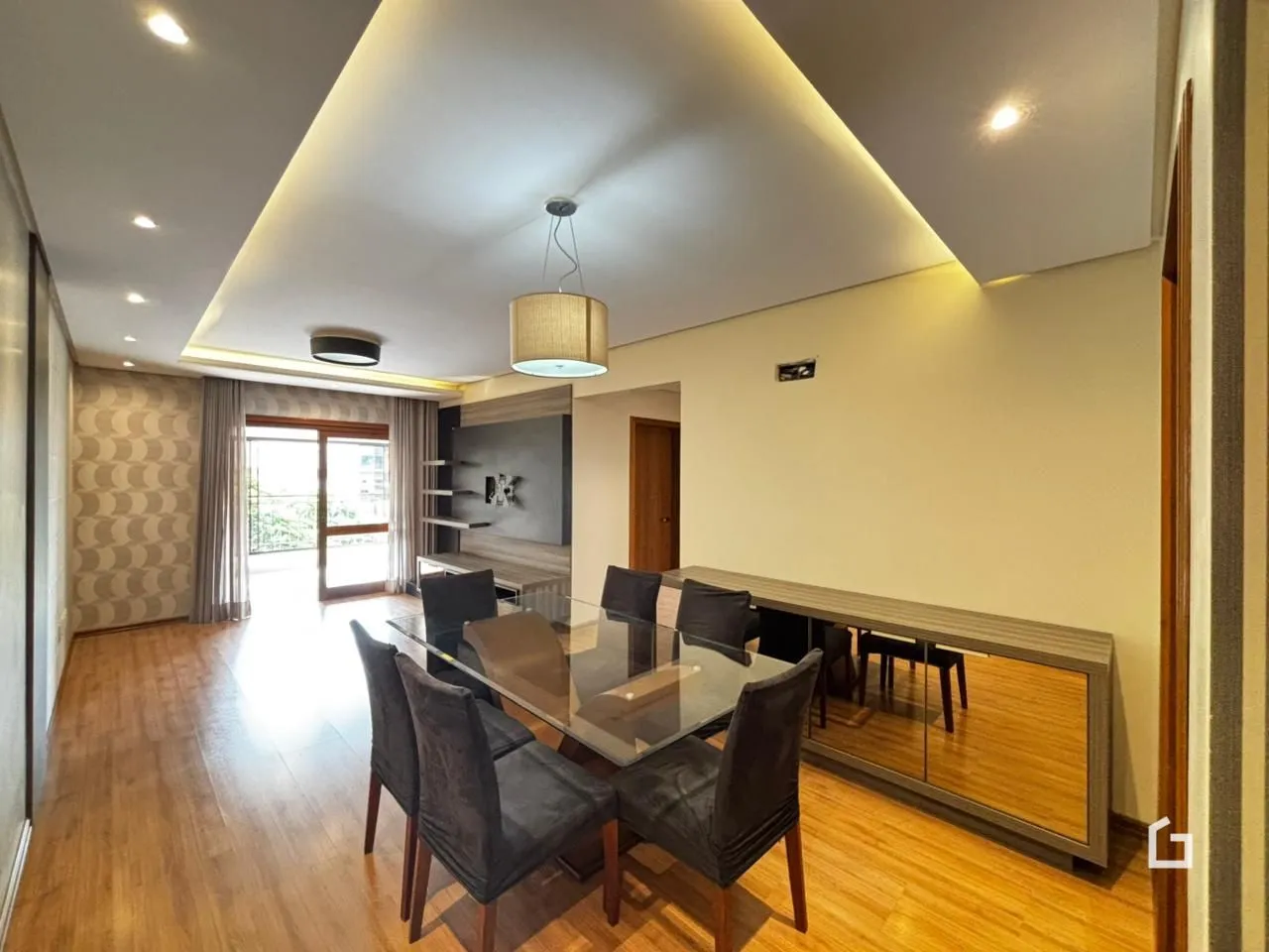 Sala de jantar com mesa de vidro e piso de madeira em um imóvel no Brasil.