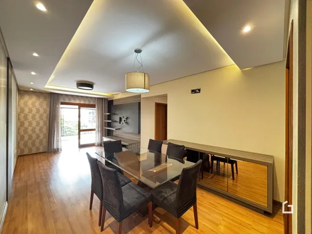Sala de jantar com mesa de vidro e piso de madeira em um imóvel no Brasil.