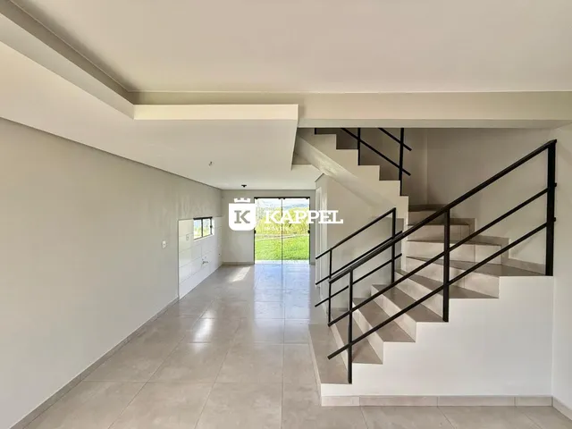 Hall de entrada com escadaria e vista para o exterior.