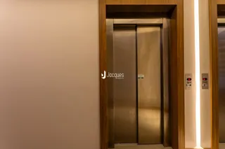 Hall de entrada com portas de elevador de aço inoxidável em um imóvel.