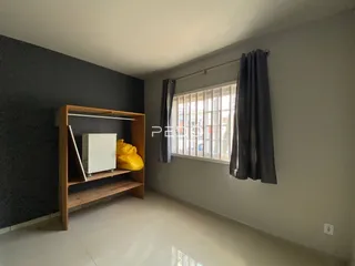 Interior de uma sala com janela e estante de madeira.