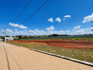 Vista da rua e terreno com vegetação ao fundo.