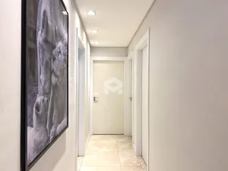 Corredor interno de uma residência com paredes brancas e piso de cerâmica clara.