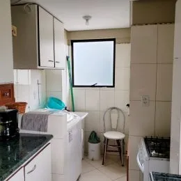 Foto interna de uma cozinha com armários brancos e bancada.