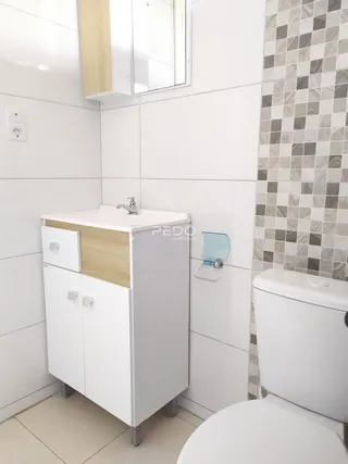 Banheiro com revestimento branco e azulejos.