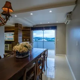 Sala de jantar com mesa de madeira e vista panorâmica da cidade.