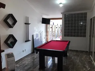 Interior de uma sala com uma mesa de jogo no piso de mármore escuro.