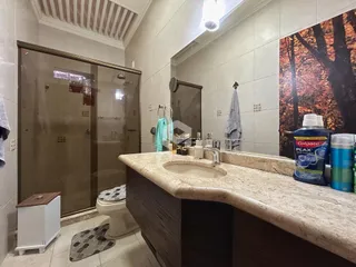 Foto de um banheiro com bancada de granito e revestimento cerâmico.