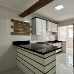 Cozinha com armários superiores brancos e bancada escura.