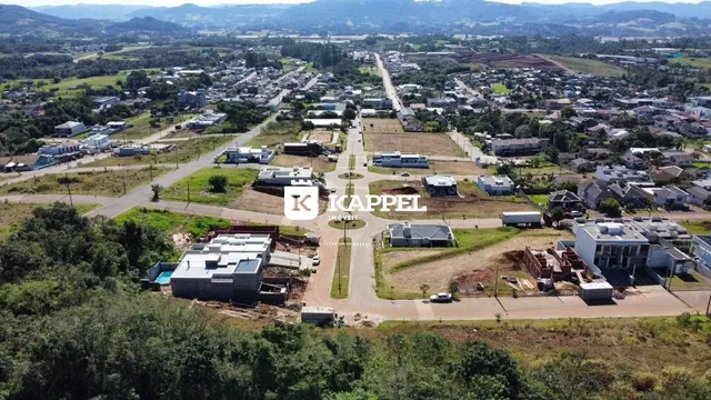 Vista aérea de uma área residencial com estradas e campos no entorno.