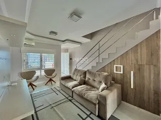 Sala de estar com sofá e escadaria em um apartamento.