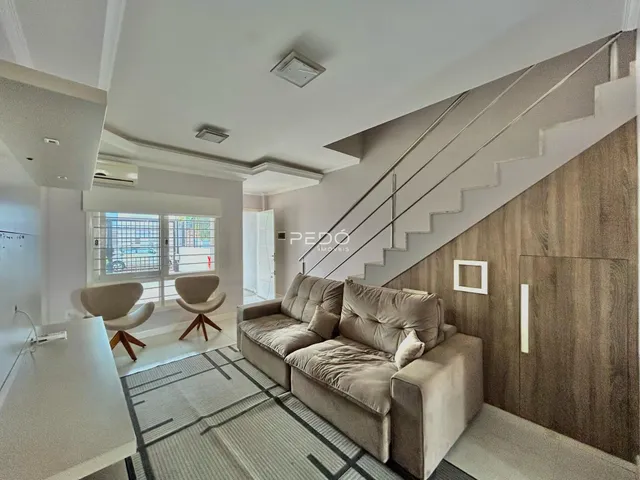 Sala de estar com sofá e escadaria em um apartamento.