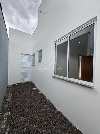 Fachada externa de um imóvel branco com uma grande janela.