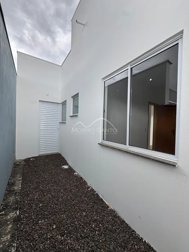 Fachada externa de um imóvel branco com uma grande janela.