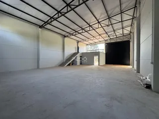 Espaço interno amplo com teto de estrutura metálica e piso de concreto.
