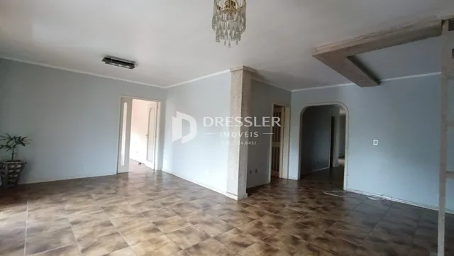 Interior de uma sala com piso de madeira e paredes cinzas.