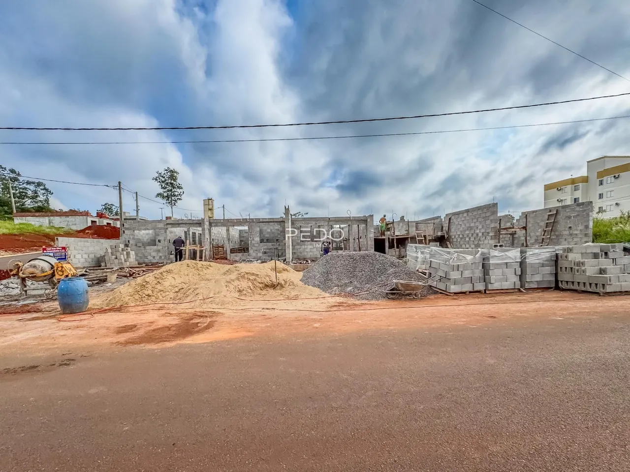 Foto da obra em construção em Lajeado, Brasil, mostrando materiais de construção e estruturas em estágio inicial.
