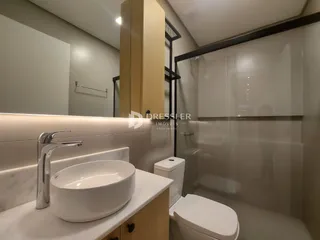 O interior de um banheiro moderno com bancada e box de vidro.