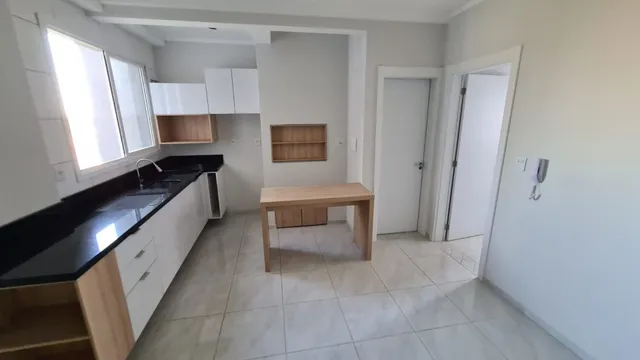Foto interna de uma cozinha com armários brancos e piso de cerâmica.