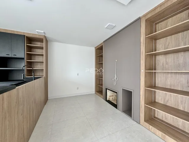 Sala de estar com cozinha integrada e armários de madeira em um imóvel em Lajeado.