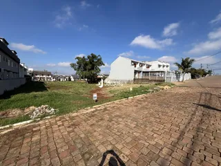 Vista externa de uma residência em Lajeado, Brasil, com área gramada e pavimento de tijolos.