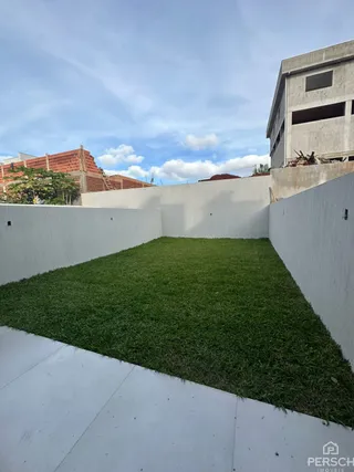 Gramado verde adjacente a um muro branco em uma propriedade.