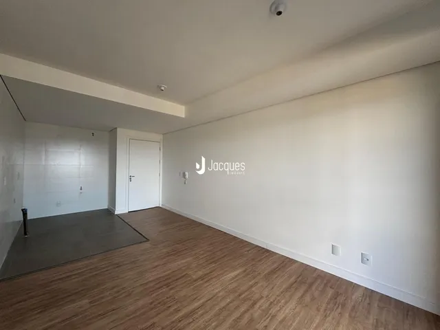 Interior de uma sala com piso de madeira e paredes brancas.
