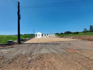 Vista de um terreno aberto com vegetação ao fundo sob um céu azul.