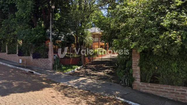 Vista externa da propriedade com muro e vegetação densa.