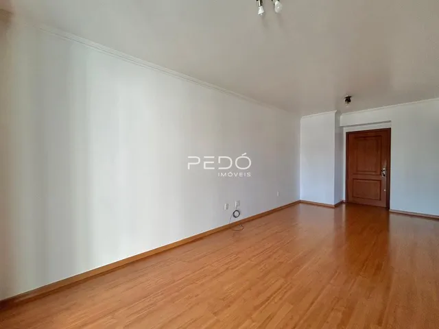 Interior de uma sala com piso de madeira e paredes brancas.