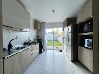 Cozinha moderna com armários brancos e piso de porcelanato, com vista para o jardim.