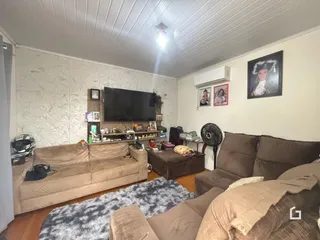Sala de estar com sofá e televisão em um imóvel.