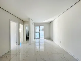 Uma área interna longa com piso de mármore branco e paredes brancas.