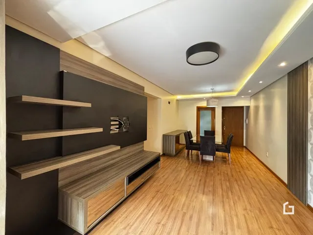 Interior de uma sala de estar com piso de madeira e painel decorativo.