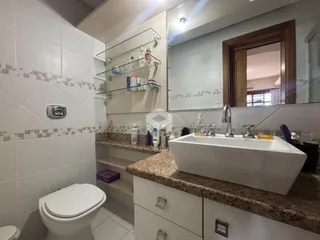 Banheiro com revestimento cerâmico e bancada de granito.