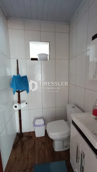 Foto de um banheiro com piso de madeira e azulejos brancos.