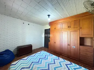Quarto com paredes de tijolo branco e armários de madeira no interior.