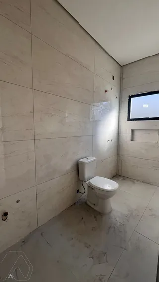 Foto interna de um banheiro com revestimento de azulejos claros.