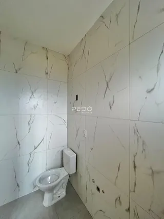 Foto de um banheiro com revestimento de azulejos brancos e veios de mármore.